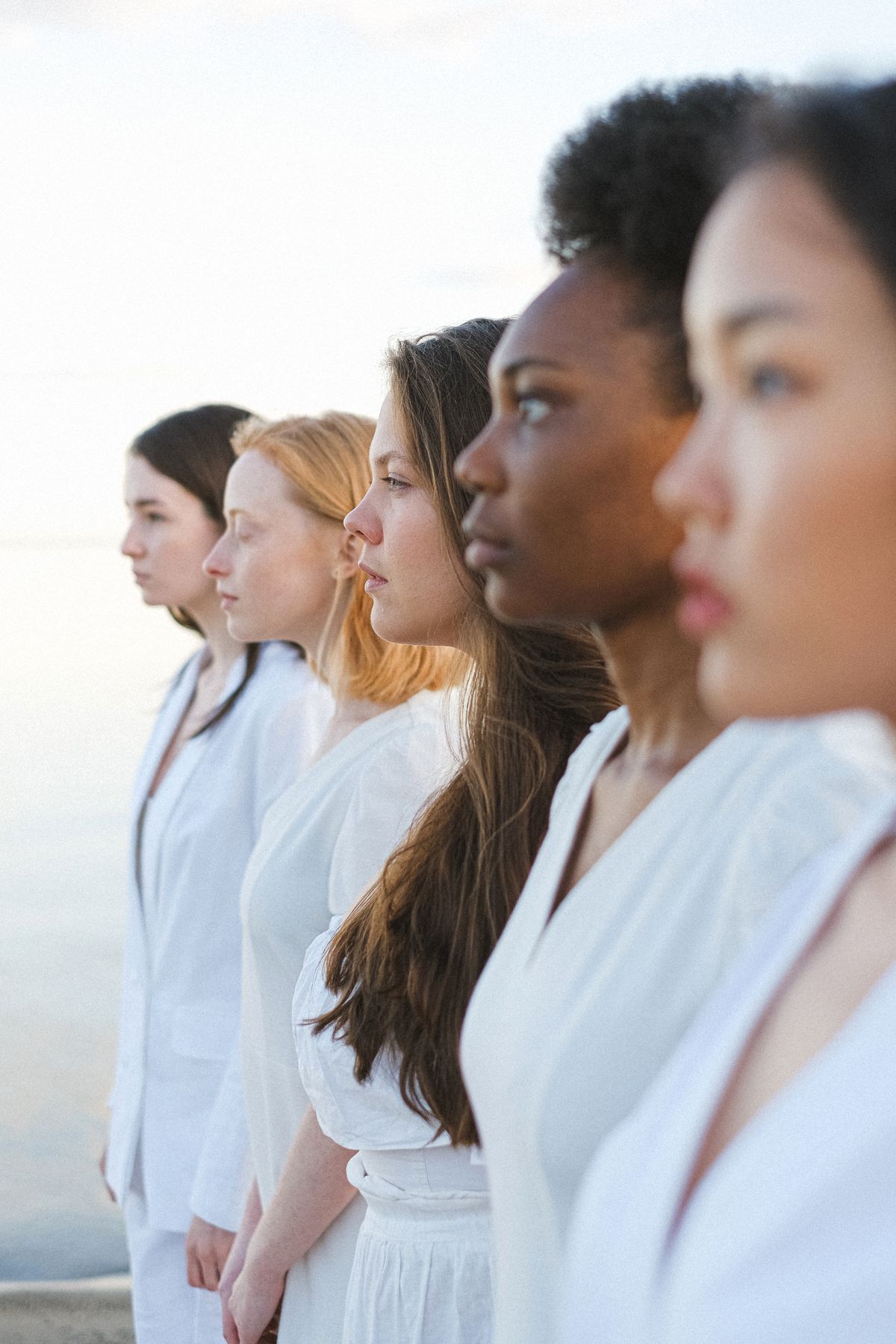 Cinq femmes d'origines différentes, alignées de profil dans la lumière